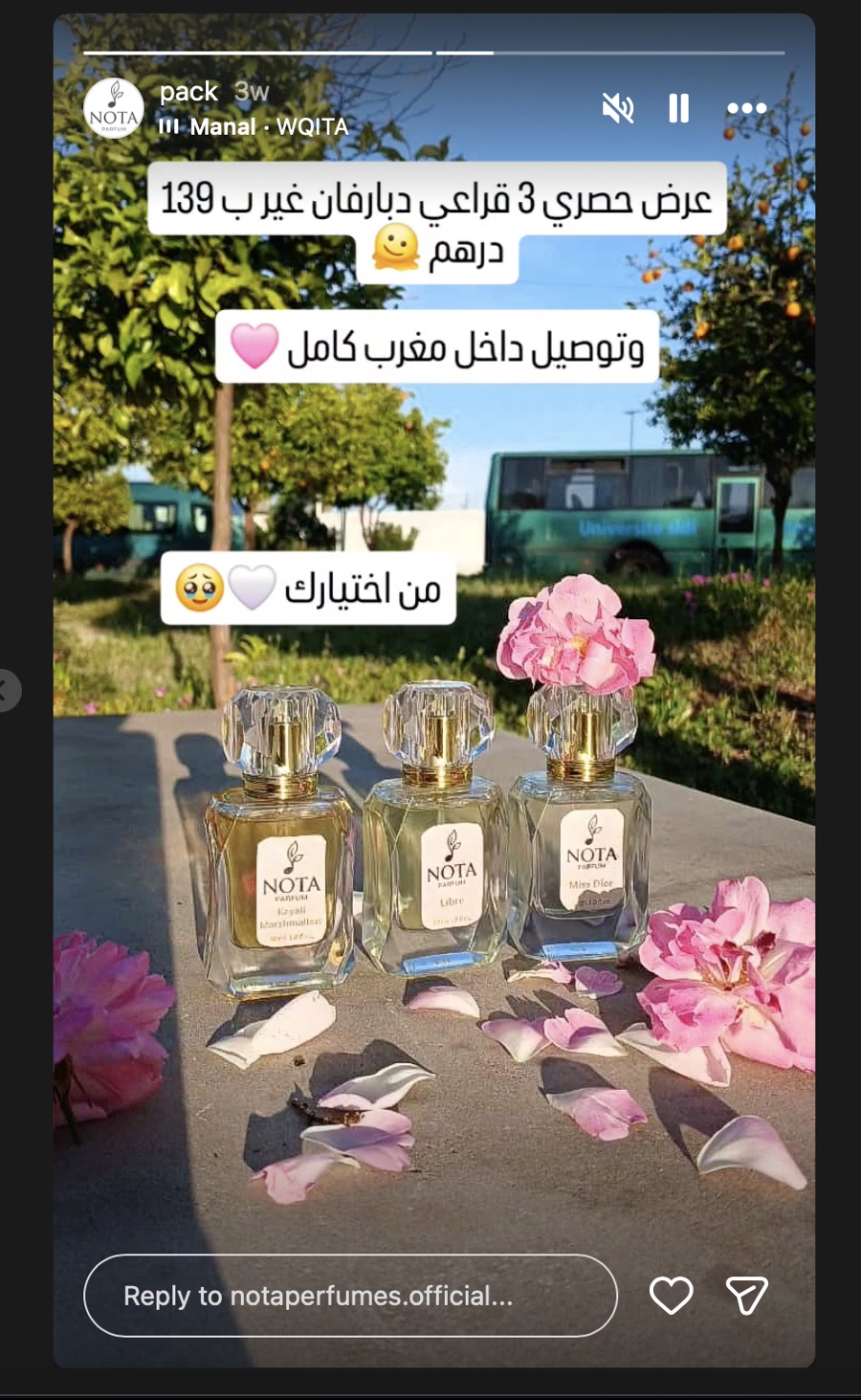 Trois flacons Nota Parfum dans un verger, parmi des pétales de rose